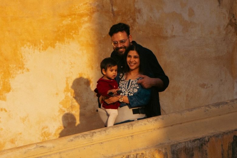 A family posing against a textured yellow wall.